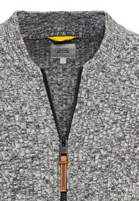 Grauer Reißverschluss-Pullover mit strukturiertem Strickmuster, ausgestattet mit einem schwarzen Reißverschluss und einem beigen Leder-Zugbändchen. Das Innere hat ein gelbes Futter.