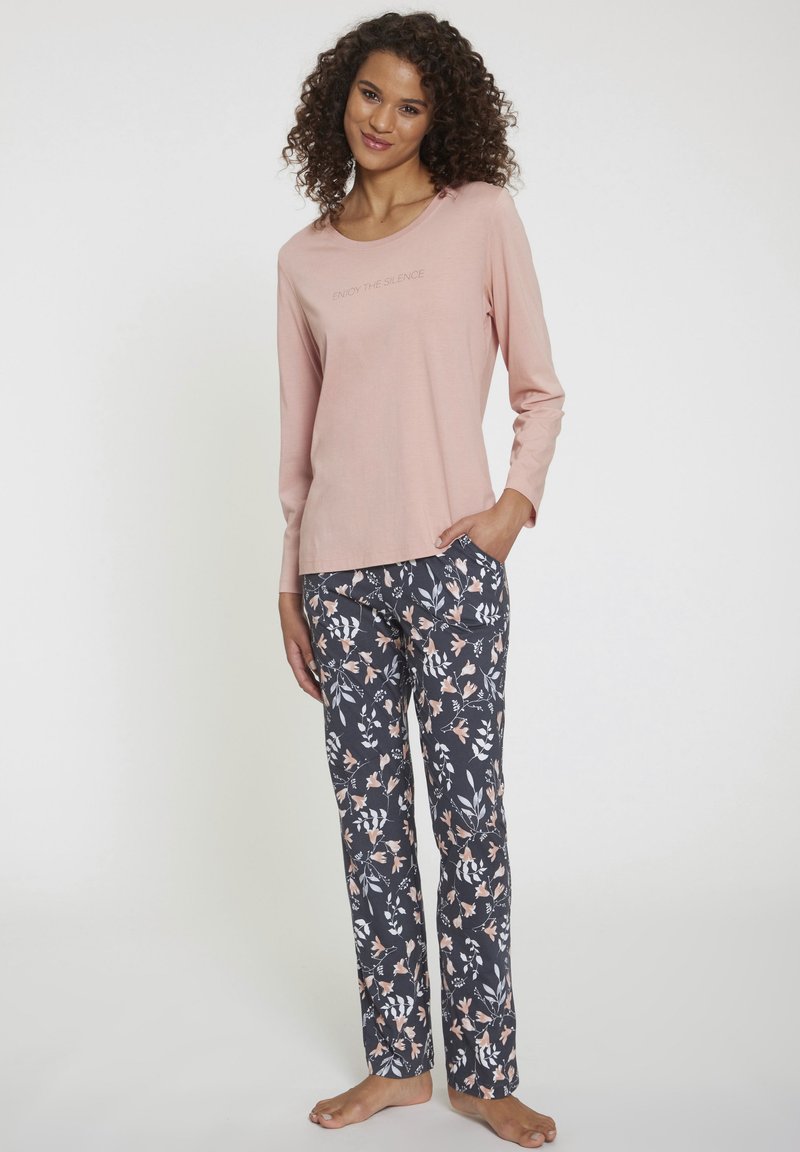 Langärmliges rosa Oberteil mit dem Text "ENJOY THE SILENCE", kombiniert mit navyfarbenen Hosen im Blumenmuster, die weiße, rosa und grüne Akzente aufweisen.