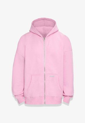 Light pink zip-up hoodie with a large hood, front pockets, and ribbed cuffs. Soft fabric with a smooth texture. Silver hardware detail on the zipper.