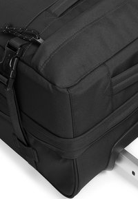Black travel bag featuring durable fabric, a sleek design, external straps, and a retractable metal handle for easy transport.