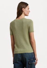 Green ribbed knit short-sleeve sweater with a round neckline and a fitted silhouette, featuring textured fabric and a subtle sheen.