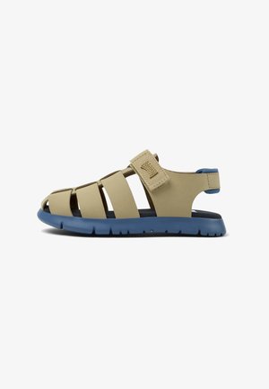 Beige rubberen sandaal met open teen ontwerp, verstelbare band en blauwe zool. Kenmerken verschillende horizontale banden en een gematteerd oppervlak.