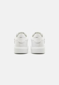 Baskets blanches en cuir avec une texture lisse, une forme arrondie et une semelle épaisse. Elles présentent des détails de logo à l'arrière et un design minimaliste.