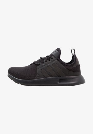 Baskets de sport noires avec dessus en mesh, fermeture à lacets et semelle rembourrée, avec trois bandes sur le côté et une boucle au talon.