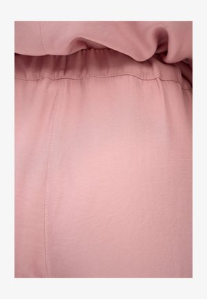 Miękka różowa tkanina z widocznymi szwami i detalem elastycznego paska w odzieży.