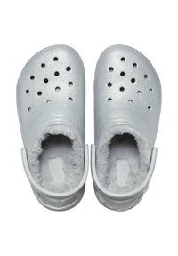 Silverfärgade tofflor med en glänsande yta, rundad form, ventilationshål och mjuk grå pälsfoder. Har justerbara bakremmar.
