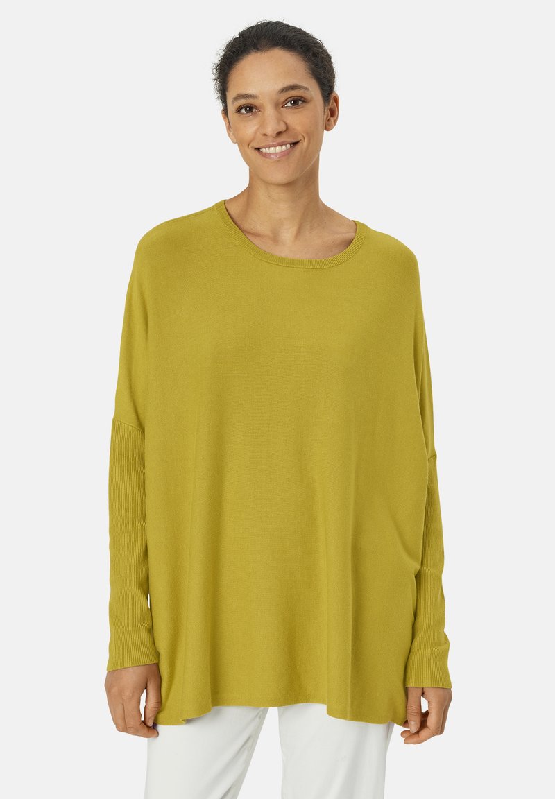 Pull en maille surdimensionné à manches longues, couleur jaune moutarde, en tissu doux, avec un col rond et des accents côtelés aux manches.