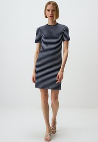 Gestreiftes Kurzarmkleid in Marineblau und Weiß mit gerippter Textur, enganliegendem Schnitt, runder Ausschnitt und knielangem Saum. Getragen mit Riemchensandalen.