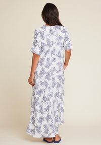 Lang hvit kjole med et blått paisley-mønster, korte volangermer og et flytende design. Glatt stoff med en gulvlengde.