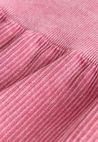 Tela rosa acanalada con una superficie texturizada y líneas verticales, que presenta pliegues suaves y una apariencia delicada.