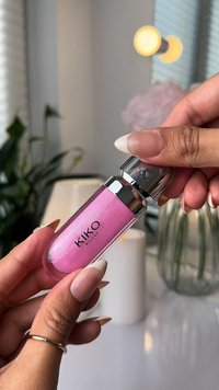 Gloss à lèvres KIKO Milano dans un tube transparent, avec un liquide rose scintillant, un capuchon argenté métallique et un embout applicateur arrondi.