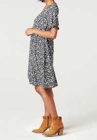 Blommönstrad klänning med en mörk marinblå bakgrund, korta ärmar och en avslappnad passform, i kombination med tanfärgade mocka ankelskor och en texturerad klack.