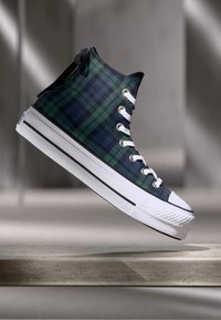 Wysokie sneakersy w niebiesko-zieloną kratę, z białą gumową podeszwą i noskiem, z białymi oczkami i sznurownikiem.