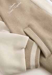 Beige ja kreem pulloveri sweatshirt, millel on tekstuuriga kangas, ribiga varrukad ja tikand "London, Ühendkuningriik".