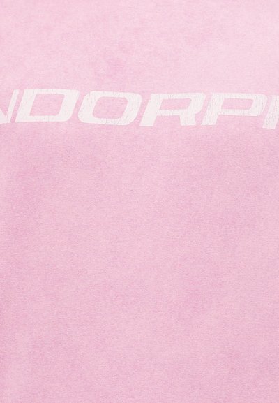 Ροζ ύφασμα με φθαρμένο, λευκό έντονο κείμενο που είναι μερικώς ορατό, εμφανίζοντας τα γράμματα "NDORPP" στο κέντρο.