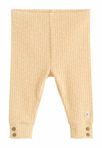 Leggings de bebé de color beige con un diseño de rayas y pequeños puntos blancos, detalles de botones en los puños y una pequeña etiqueta con una flor azul cerca del tobillo.