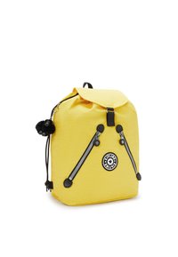 Gul ryggsäck med snörstängning, svarta detaljer, två framfickor med dragkedja och en dekorativ svart apnyckelring.