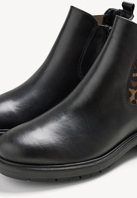 Stivaletti neri in pelle con un design elegante, pannelli laterali elastici e un accento in stampa leopardata testurizzata all'interno. Suola in gomma per la trazione.