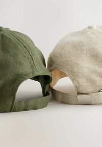 Dwie czapki: jedna w ciemnozielonym materiale, a druga w jasnym beżu z teksturowanym wykończeniem. Obie mają regulowane paski i wygięte daszki.