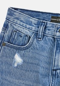 Shorts in denim blu con toppa sfrangiata e leggere sfumature di usura. Presentano una tasca frontale, chiusura con bottone metallico e cintura cucita.