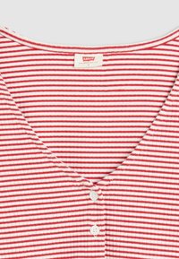 Röd- och vitrandig t-shirt med V-ringning och tre knappar. Tillverkad av mjukt tyg, har ribbad struktur och korta ärmar.
