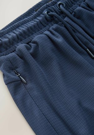 Navy blue athletic shorts made of textured fabric featuring an elastic waistband with drawstring and a zippered side pocket.