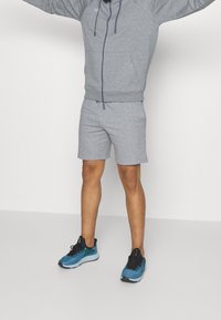 Grau Hoodie mit Kordeln und passenden grauen Shorts. Die Schuhe sind aus blauem Mesh mit schwarzen und grünen Akzenten. Einfaches, sportliches Design.