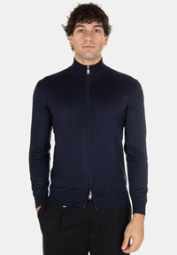 Maglione con zip di colore blu navy, colletto alto, vestibilità slim, texture a coste e zip argentata. Maniche lunghe e dettaglio logo discreto all'orlo.