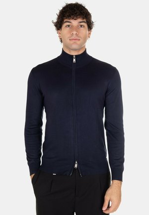 Maglione con zip di colore blu navy, colletto alto, vestibilità slim, texture a coste e zip argentata. Maniche lunghe e dettaglio logo discreto all'orlo.