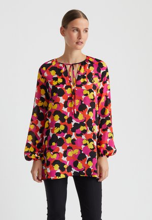 Blouse à manches longues en tissu transparent à motif floral avec des couleurs rose, jaune et noir. Dotée d'un décolleté en trou de serrure avec un détail de lien.