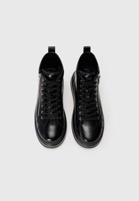 Black leather high-top sneakers with side zippers and black laces, displayed from above on a white background.