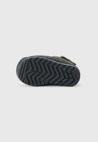 Cipőtalp zigzag mintázattal, fekete gumiból készült, lekerekített forma, texturált felülettel, látható márkázással.
