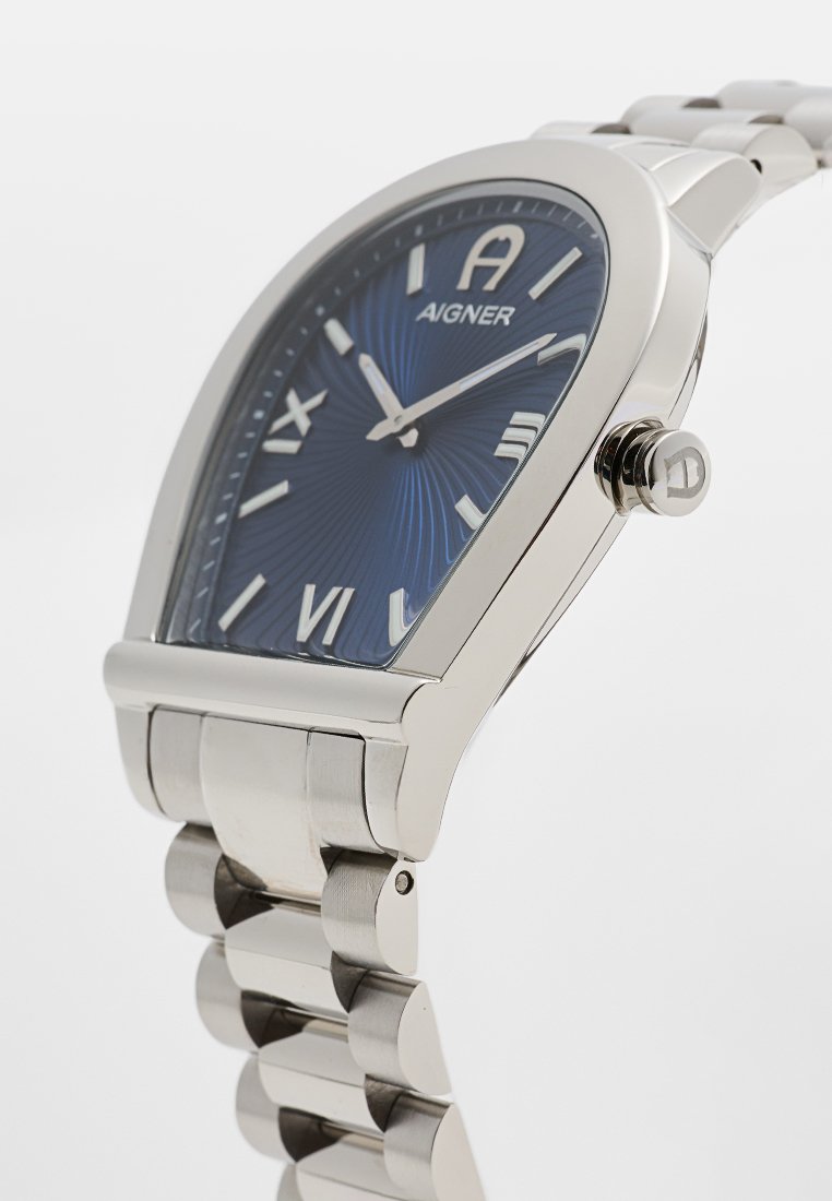 Silberfarbene Edelstahl-Uhr mit blauem strukturiertem Zifferblatt, länglichem Gehäuse, römischen Ziffern als Indizes und einer dekorativen Krone.