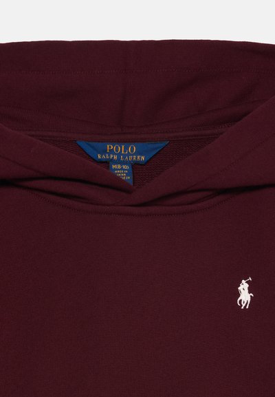 Κοντινό πλάνο από μπορντό πουλόβερ Polo Ralph Lauren που δείχνει μπλε και χρυστή ετικέτα και μικρό λευκό κεντημένο λογότυπο παίκτη πόλο στο στήθος.