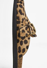 Leopard print slip-on shoe with a textured suede upper, black trim, side buckle detail, and a cork-like sole.