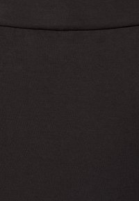 Černá elastická látka, hladká textura, přiléhavý střih a pas. Převážně jednobarevné, bez viditelných vzorů nebo ozdob.