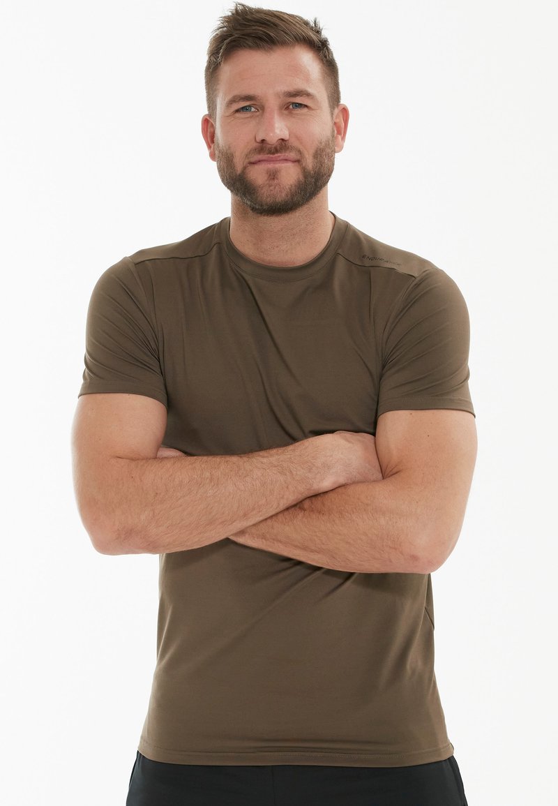 Kortærmet, tætsiddende t-shirt i mørkeoliven, lavet af let, glat stof. Har rund hals og minimale sømme.