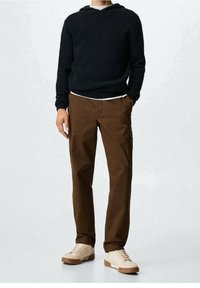 Hoodie en maille noire avec un motif texturé, associé à un pantalon cargo marron avec poches latérales et des baskets beige à semelle claire.