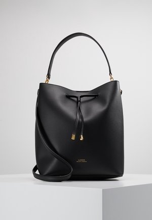 Black leather bucket bag with gold accents, adjustable shoulder strap, and drawstring closure, displayed on white podium.