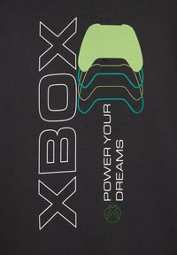 Zwart fabric heeft witte en groene tekst met een Xbox-controllerontwerp boven de zin "POWER YOUR DREAMS" en een groen Xbox-logo.