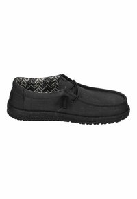 Schwarze Slip-On-Schuhe aus Canvas mit einem strukturierten Stoffoberteil, gummierter Sohle und einem Innfutter mit Wellenmuster. Verfügt über ein Schnürdettail.
