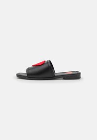 Black slide sandal with a red fabric heart applique, flat sole, open toe, and smooth texture. Features subtle stitching and logo on the sole.