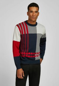 Mehrfarbiger Strickpullover mit blauen, roten, grauen und weißen Blöcken in verschiedenen Mustern, einschließlich Streifen und Karos. Rundhalsausschnitt.