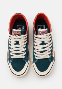 Vysoké tenisky z modré plátno s bílými tkaničkami, červenými akcenty a kostkovaným vzorem na boku. Plochá gumová podrážka.