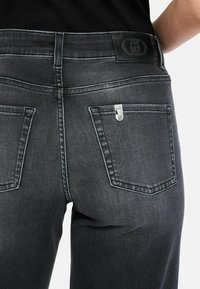 Donkergrijze denim jeans met een lichte stretch, voorzien van een leren logo patch op de taille en zilverkleurige hardware op de achterzakken.