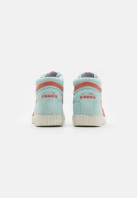 Une paire de baskets en daim Diadora bleu clair et corail vue de l'arrière sur un fond blanc.