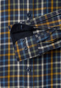 Overhemd met knopen in een navy, gele en teal geruit patroon. Gemaakt van geweven stof met een zachte textuur en contrasterende blauwe knopen.
