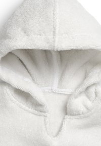 Valkoinen huppupyyhe, joka on valmistettu pehmeästä ja teksturoidusta kankaasta. Sisäpuoli on plush, ja siinä on V-muotoinen kaula-aukko sekä ommellut saumat kestävyyden vuoksi.