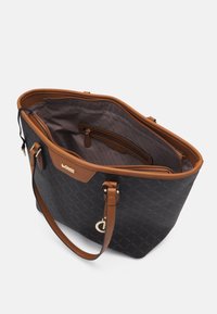 Schwarze Canvas-Tasche mit braunen Lederakzenten, offenes Oberteil und geräumiges Innenfach mit einem Reißverschlussfach. Diamantmuster auf der Außenseite.