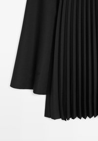 Zwarte plooidenimrok met een gladde textuur, gekenmerkt door een asymmetrische zoom en fijn gestructureerde plooien voor extra detail.
